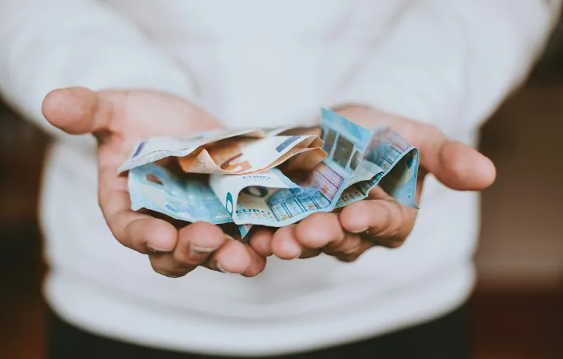 A person holding euro banknotes, symbolising charitable giving